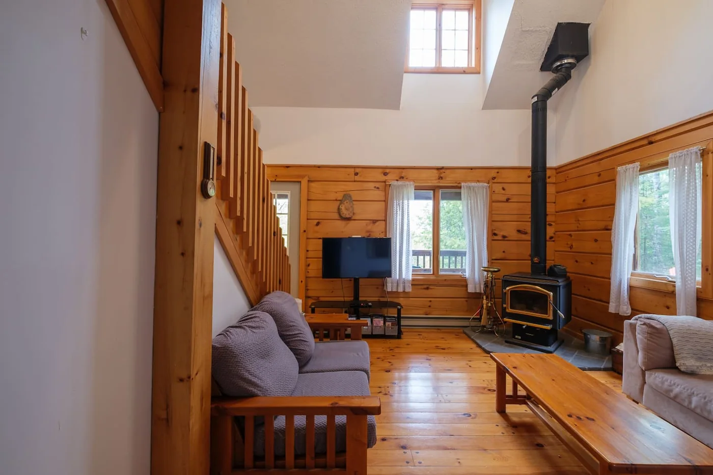 A warm wood-lined living room with comfortable seating and a wood-burning stove